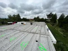 Gotowy do zalania strop filigran, z zielonymi oznaczeniami i widocznym żurawiem w tle.