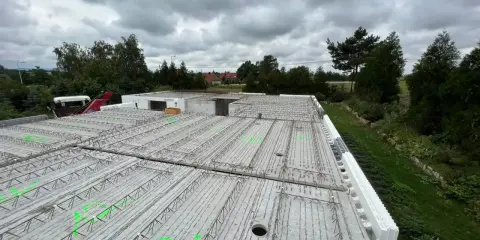 Gotowy do zalania strop filigran, z zielonymi oznaczeniami i widocznym żurawiem w tle.