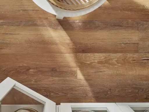 Drewnopodobne panele laminowane czy winylowe na podłodze, z fragmentem białej szafki i blatu.