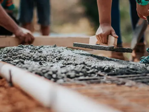Dłoń wyrównująca świeży beton kielnią na budowie.