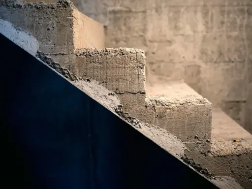 Surowe schody betonowe, idealne do rozważenia, jak tanio wykończyć schody betonowe. Tekstura betonu i siatka zbrojeniowa.