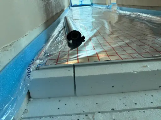 Układanie styropianu pod wylewkę. Warstwa izolacji z folią aluminiową i taśmą brzegową.