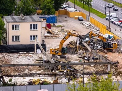 Dwa koparki pracują przy wyburzaniu budynku. Szacowany koszt wyburzenia domu 100m2 może być wysoki.