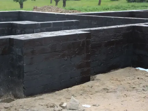 Fundament czarny, z cegły, z widocznym izolacyjnym materiałem. To miejsce, gdzie powstanie dom, a jego solidne podstawy mają disprobit.